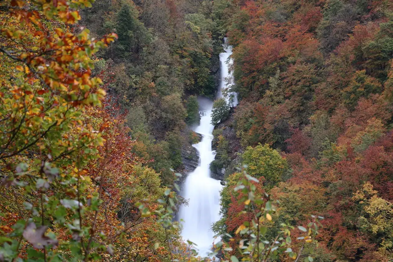 La cascade du Bief de la Ruine d&eacute;vale une pente rocheuse, entour&eacute;e d'une for&ecirc;t aux couleurs flamboyantes de l'automne.