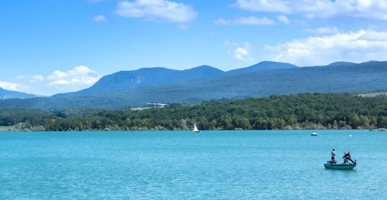 Le lac de Montbel, un voilier et un bateau de p&ecirc;che sous un ciel bleu.