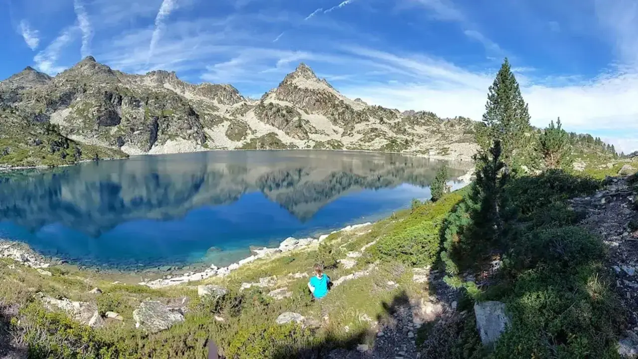 Un enfant en t-shirt bleu admire le reflet parfait des montagnes dans le lac du cirque de Morgon. Un paysage alpin spectaculaire.