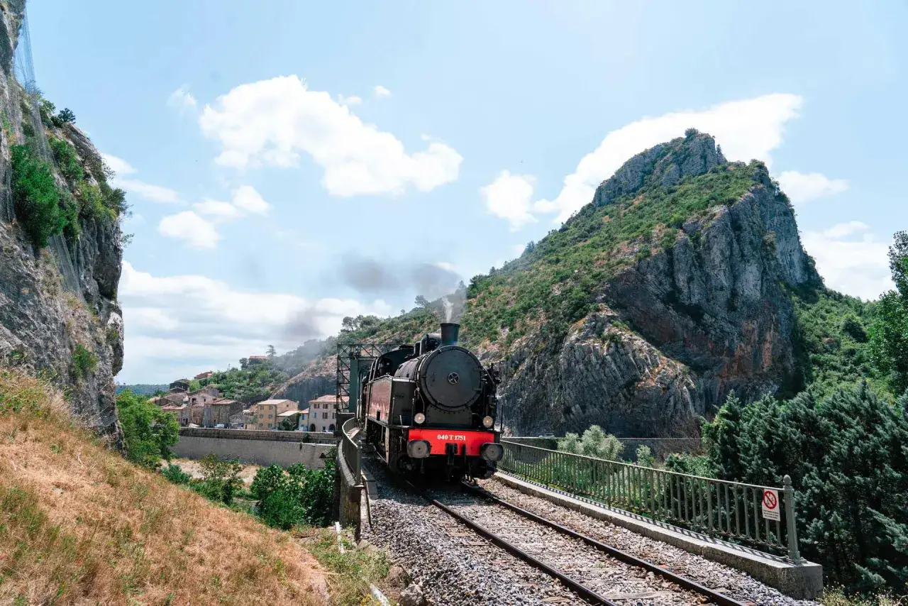 Le petit train des C&eacute;vennes traverse un paysage montagneux. La dur&eacute;e du trajet est un voyage dans le temps.