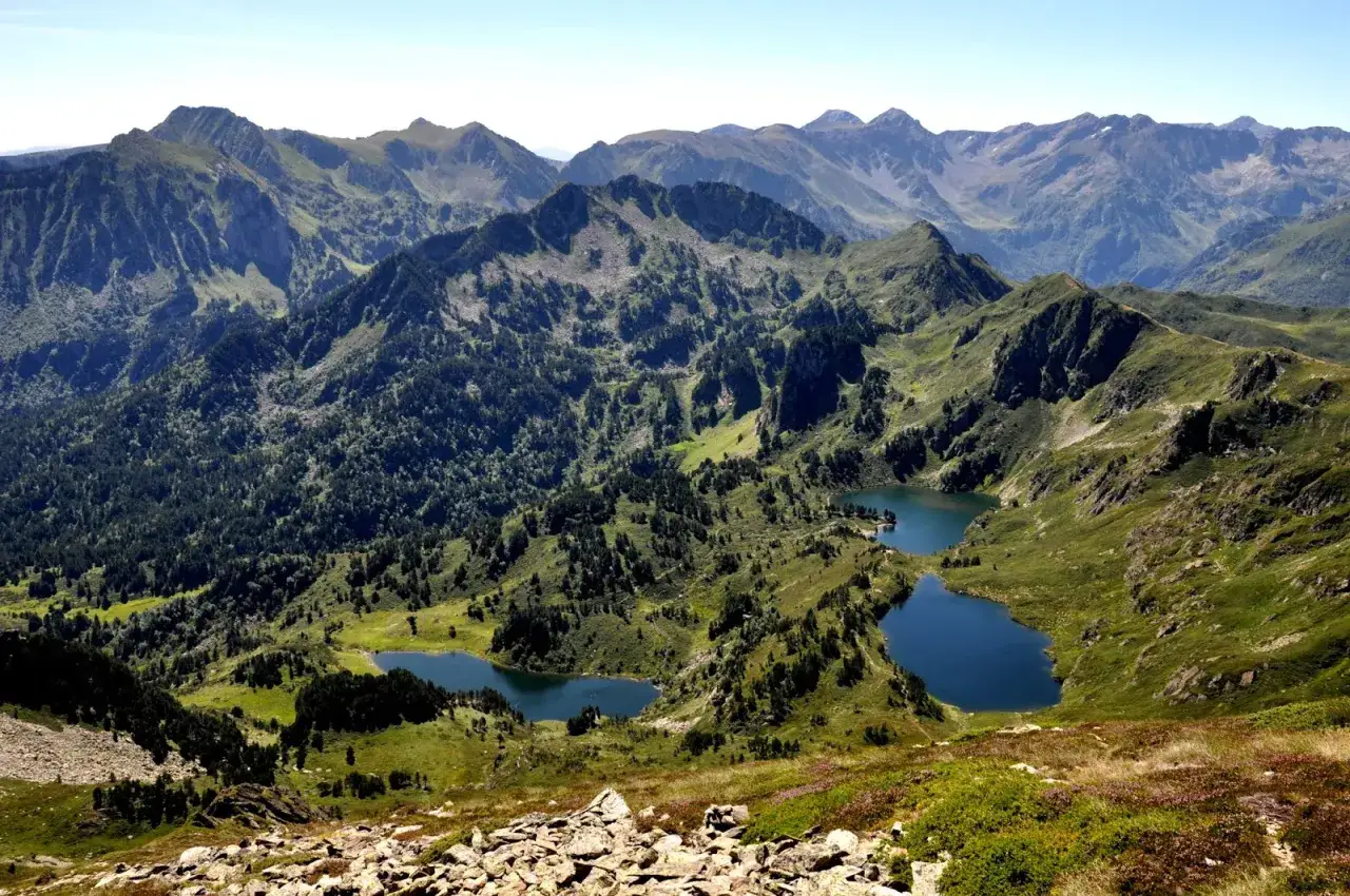 Vue panoramique depuis le pic de Tarbesou, avec des lacs d'altitude bleus nich&eacute;s au c&oelig;ur de montagnes verdoyantes et bois&eacute;es.