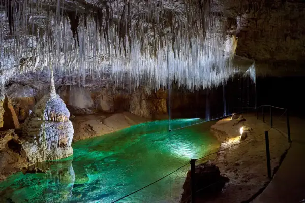 Émerveillement dans la grotte de Thaïs : stalactites fines comme des fils, eau émeraude et formations rocheuses spectaculaires.