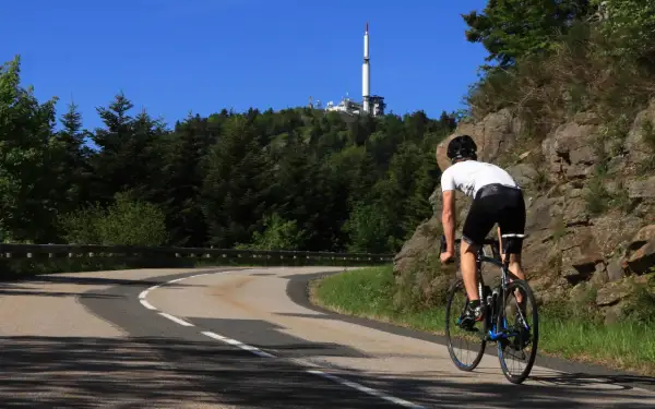 Cycliste en ascension vers le col de l'Oeillon, avec une tour de télécommunication visible au sommet.