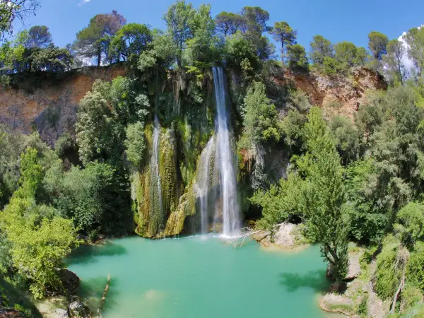 La cascade de Sillans, un spectacle naturel impressionnant, se jette dans un bassin d'eau turquoise entouré de verdure luxuriante.