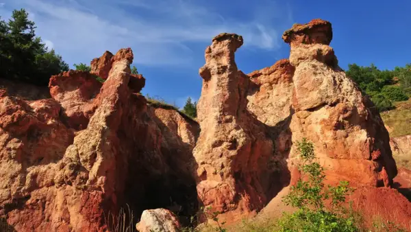 Les formations rocheuses ocreuses de la vallée des Saints en Auvergne, sculptées par le temps, se dressent sous un ciel bleu éclatant.