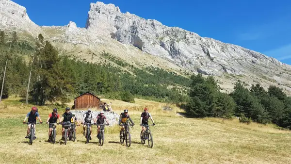 Groupe de cyclistes explorant le col de Gleize, avec une imposante montagne en arrière-plan.