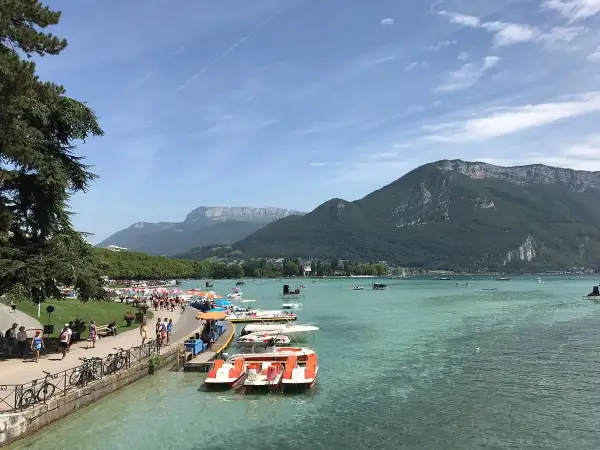 Vue animée de la plage de l'Impérial avec des pédalos et des montagnes en arrière-plan.